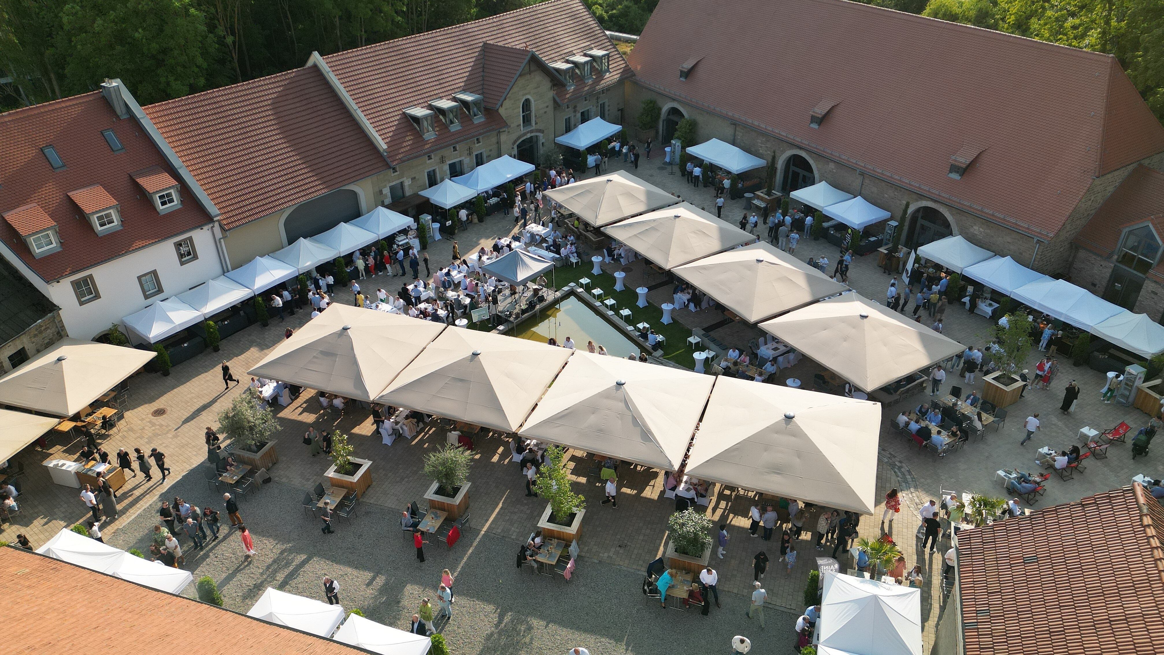 Viele Gäste im großen Außenbereich der Eventlocation Gut Wöllried Würzburg bei einem sommerlichen Firmenevent