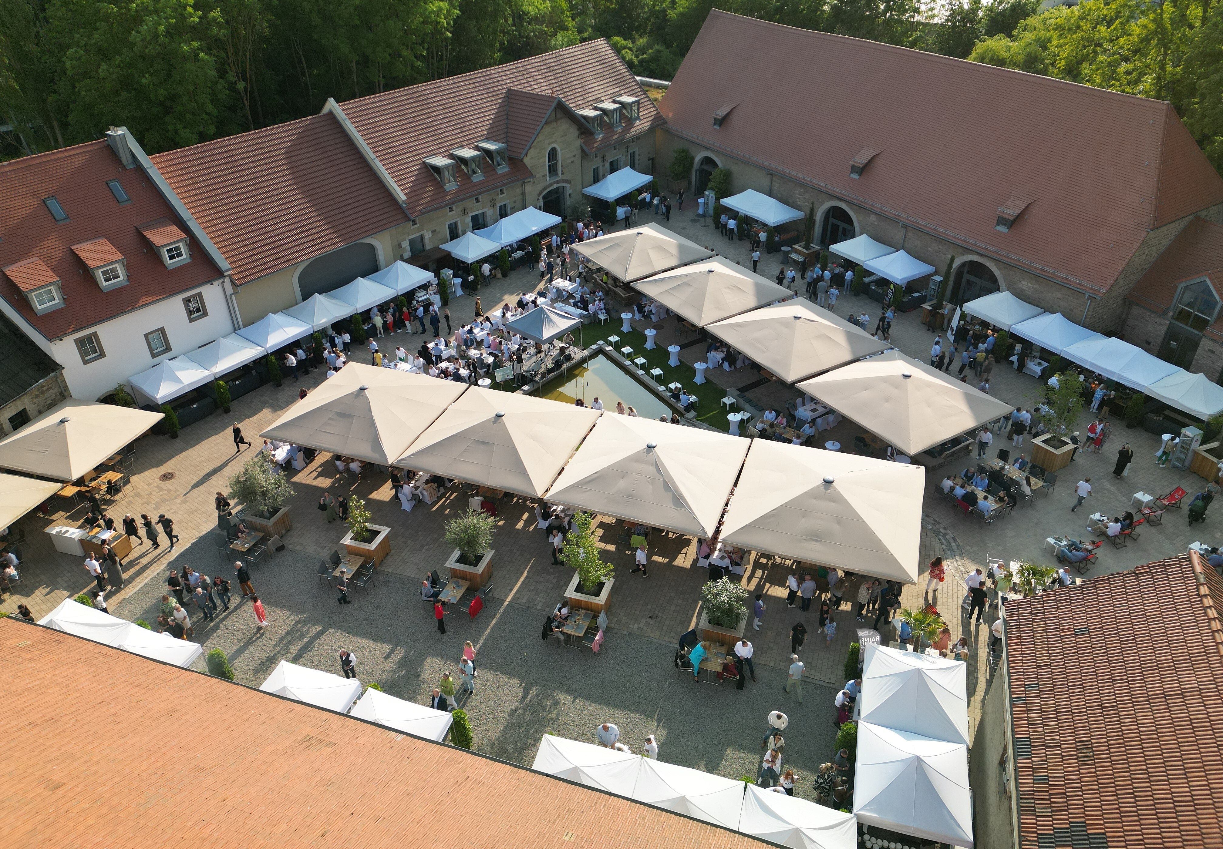 Viele Gäste im großen Außenbereich der Eventlocation Gut Wöllried Würzburg bei einem sommerlichen Firmenevent